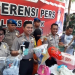 Kapolres AKBP Wahyu S Bintoro memamerkan tersangka beserta HP dan baju milik korban. foto: SYUHUD/ BANGSAONLINE