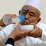 Prof. Dr. KH. Asep Saifuddin Chalim saat memperagakan memasukkan garam krosok yang dilarutkan dalam air mineral ke dalam hidung dan mulut untuk merontokkan virus corona di sela salat malam dan istighatsah di Pondok Pesantren Amanatul Ummah Surabaya, Kamis (22/7/2021). foto: mma/ bangsaonline.com