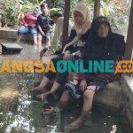 Mbah Koripah ditemani salah satu anak perempuan saat terapi ikan di Kolam Sumber Banteng. Foto: MUJI HARJITA/ BANGSAONLINE