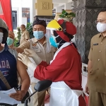 Pengemudi ojek online saat menerima suntikan vaksin dengan tetap duduk di sepeda motornya disaksikan oleh Kepala Dinas Kesehatan Kota Kediri dr. Fauzan Adima di Balai Kota Kediri. (foto: MUJI HARJITA/BANGSAONLINE)