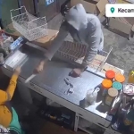 Tangkapan layar video rekaman CCTV saat pelaku mengancam karyawan menggunakan pisau.