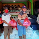 KH. Khusni (kanan) saat membagikan beras dan sembako pada para tukang becak dan warga kurang mampu di lingkungan rumahnya. foto: HERMAN/ BANGSAONLINE