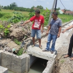 Nuryono Sugiraharjo anggota DPRD Kota Mojokerto (pakai peci) bersama warga menunjukkan saluran air yang terhalang tiang listrik. Ia berharap keluhan warga segera terpecahkan. Foto: Yudi EP/ BANGSAONLINE.com