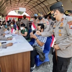 Kapolda Jatim memberikan bendera ke warga di lokasi vaksinasi. (foto: ist)