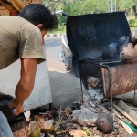 Triono saat mengupas degan yang sudah dibakar. foto: MUJI HARJITA/ BANGSAONLINE