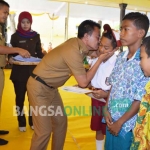 Bupati Jombang, Nyono Suharli Wihandoko bersama Ketua GNOTA Kabupaten Jombang, Tjaturina Wihandoko menyerahkan bantuan biaya pendidikan di Pendopo Kabupaten Jombang, Rabu (28/12). foto: ROMZA/ BANGSAONLINE