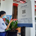 Seorang siswa melakukan scan barcode Aplikasi PeduliLindungi.