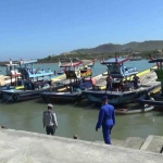 Perahu nelayan yang diparkir karena gelombang laut sedang tinggi.