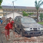 Sebuah mobil tertimpa bangunan yang ambruk akibat diterjang angin kencang.