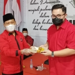 Ketua DPC PDI Perjuangan Kabupaten Kediri, Murdi Hantoro saat menyerahkan potongan tumpeng kepada Bupati Kediri Hanindhito Himawan Pramana disaksikan oleh Ketua DPRD Kabupaten Kediri Dodi Purwanto (duduk). foto: MUJI HARJITA/ BANGSAONLINE