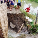 Warga berupaya membendung air menggunakan karung berisi tanah serta bambu.