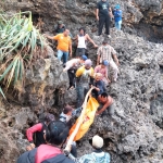 Warga membantu petugas mengevakuasi jasad korban dari tebing karang.