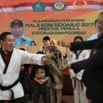 SATU PUKULAN: Ketua Umum KONI Sidoarjo M Franki Efendi memukul papan hingga pecah usai menerima sabuk hitam Taekwondo, Minggu (17/12) sore. foto: ist