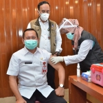 Plh. Bupati Gresik Drs. Abimanyu Poncoatmojo Iswinarno, M.M., didampingi Kadinkes Gresik drg. Saifudin Ghozali saat disuntik vaksin Covid-19. (foto: SYUHUD/ BANGSAONLINE)