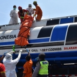 Petugas sedang berusaha menurunkan jasad korban dari atas truknya.