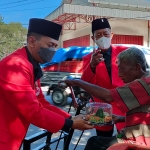 Wakil Ketua DPC PDIP Kediri Bidang Pemenangan Pemilu Tri Efendi (kiri) dan Bendahara Gatot Priyono saat menyerahkan tumpeng mini kepada salah satu penyandang disabilitas. Foto: Muji Harjita/ BANGSAONLINE.com