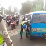 Petugas saat menggembosi salah satu ban mobil yang parkir di atas jembatan kampung putih, Kamis (20/07). foto: IWAN IRAWAN/ BANGSAONLINE