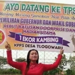 Salah satu panitia menunjukkan banner informasi pencoblosan berhadiah kambing. Foto: ist