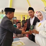 Salah satu mempelai menunjukkan buku nikah usai melaksanakan akad.