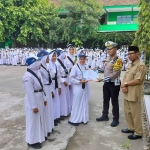 Petugas dari Satlantas Polres Ngawi saat memberi bingkisan kepada pelajar yang mengikuti sosialisasi.