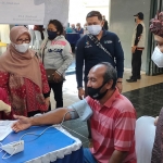 Anggota Komisi IX DPR RI dari Fraksi Partai Nasdem, Nurhadi, S.Pd. (kanan) dan dr. Indra Kurnia Sari, M.Kes., Koordinator Ispa dari Kemeskes RI saat menyaksikan salah satu warga yang diperiksa tensi darahnya sebelum divaksin. foto: MUJI HARJITA/ BANGSAONLINE