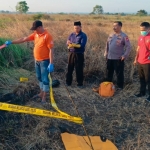 Petugas memasang garis polisi di lokasi penemuan mayat.