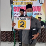 Abdul Khamid menunjukkan nomor urut 2 hasil undian Pilkades Yosowilangun. foto: SYUHUD/ BANGSAONLINE