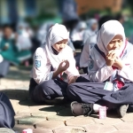 Kegiatan siswa makan telur bersama di halaman SMPN 4 Kota Madiun sebelum masuk kelas.