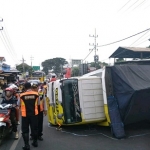 Truk yang terguling dihantam mobil HRV dan menimpa rumah.