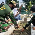 Anggota Kodim 0817/Gresik bersama para pelajar saat kerja bakti membersihkan makam pahlawan. (foto: ist)