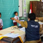 Petugas Dispendukcapil Kota Kediri saat mengambil foto dua siswa SD. Foto: Ist