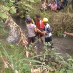 Petugas dibantu warga saat mengevakuasi mayat korban.