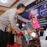 Kapolres Kediri AKBP Lukman Cahyono saat menyerahkan bingkisan kepada salah satu anak yatim usai divaksin. (foto: Ist.)