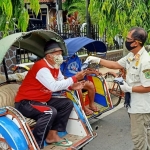 Kasatpol PP Trenggalek Triadi Atmono saat memberikan masker pada para tukang becak. foto: HERMAN/ BANGSAONLINE