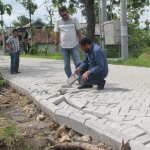 Para petugas saat memeriksa jalan paving yang bergelombang dan lepas dari pasangannya.