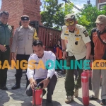 Lurah Gunung Gedangan, Andika (kemeja putih), dan Kepala Satpol PP Kota Mojokerto, Modjari,  saat memadamkan kobaran api dalam simulasi penanganan kebakaran. Foto: YUDI EKO PURNOMO/BANGSAONLINE