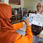 Petugas saat melayani salah satu keluarga penerima manfaat yang mengambil bansos BPNT/PKH. Foto: Ist.