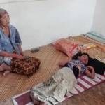 Nenek Simpen (70) saat sedang menunggui cucunya, Fitri Eka (13) yang lumpuh tidur di lantai beralas anyaman bambu. foto: syuhud/BANGSAONLINE