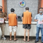 Kedua tersangka saat diapit petugas Polrestabes Surabaya.