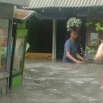 Warga Desa Tlogobendung, Kecamatan Gresik, Kabupaten Gresik, saat berada di luar rumah ketika banjir. Foto: SYUHUD/ BANGSAONLINE