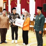 Pj Gubernur Adhy Karyono didampingi Ketua Baznas Jatim KH Ali Maschan Moesa menyerahkan bantuan beasiswa satu keluarga satu sarjana, beasiswa SLTA, dan modal usaha UMKM kepada 6 perwakilan penerima.