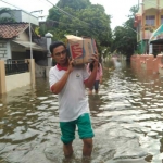 Korban banjir luapan Bengawan Solo di Kecamatan Bungah membawa bantuan air mineral. foto: SYUHUD/ BANGSAONLINE