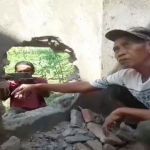 Seorang tukang sedang menunjukkan bagian tembok yang dibobol maling.