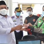 Bupati Gresik, Gus Yani, didampingi Kadishub Kabupaten Gresik, Tursilowanto, saat menyerahkan bantuan kepada pengemudi ojek daring. Foto: SYUHUD/ BANGSAONLINE.com