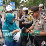 Kapolres Jombang AKBP Agung Marlianto saat memberikan cokelat kepada pengendara yang tertip berlalulintas, Selasa (29/11). foto: RONY S/ BANGSAONLINE