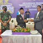 Bupati Gresik Fandi Akhmad Yani didampingi Ketua KONI Anis Ambiyo Putri menyerahkan potongan tumpeng kepada Moch Yusron. foto: SYUHUD/ BANGSAONLINE