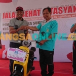 Kades Sukomulyo, Subiyanto, saat menyerahkan hadiah utama motor listrik kepada pemenang. Foto: SYUHUD/BANGSAONLINE