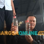 Petugas saat menunjukkan miras jenis Arak Bali yang diamankan. Foto: AKINA NUR ALANA/BANGSAONLINE