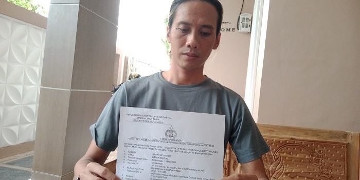 Korban saat menunjukkan surat laporan kepada awak media.